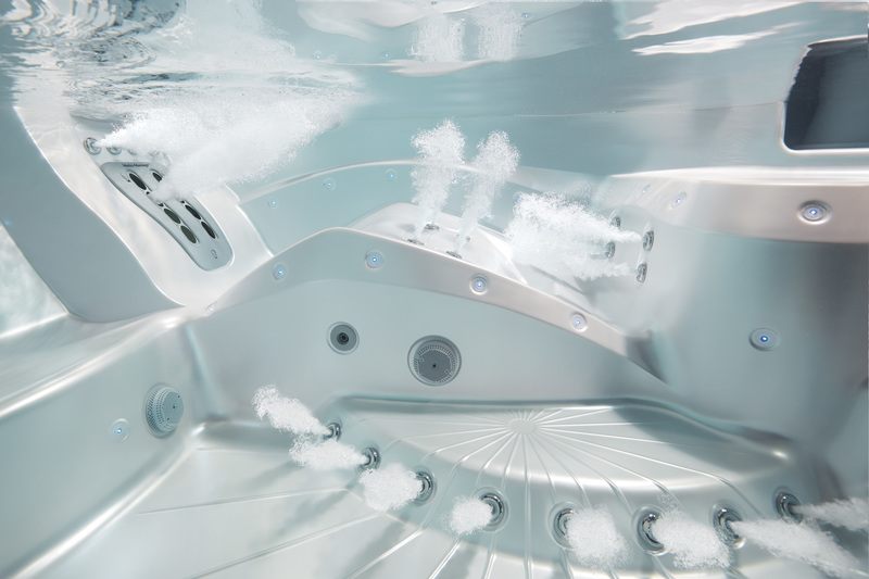 Underwater view of a hot tub with numerous jets and air bubbles rising to the surface.