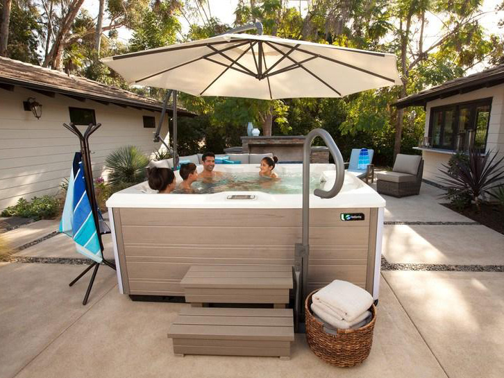 A spa umbrella, steps, handrail, and towel tree augment this Limelight® Pulse hot tub.