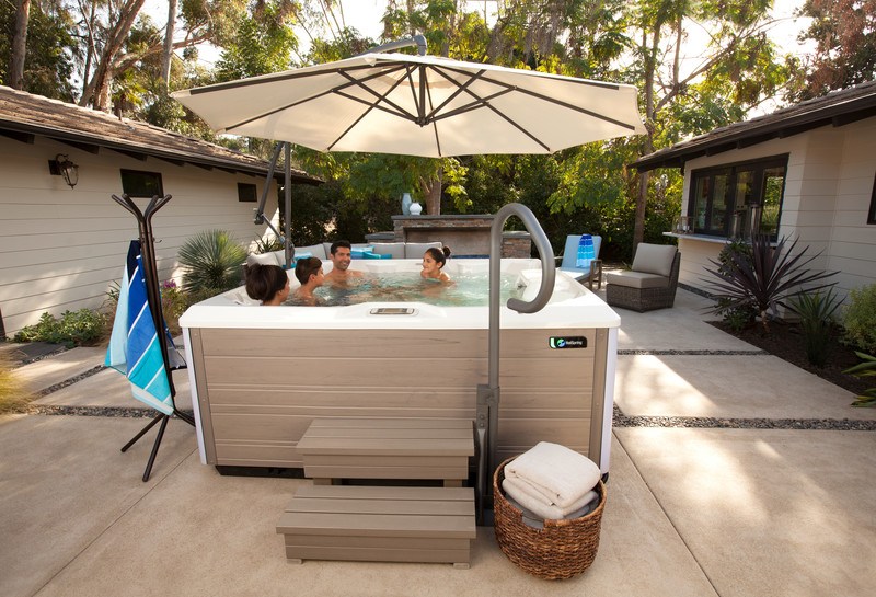 A spa umbrella offers shade to a couple and their two kids in the summer sun.